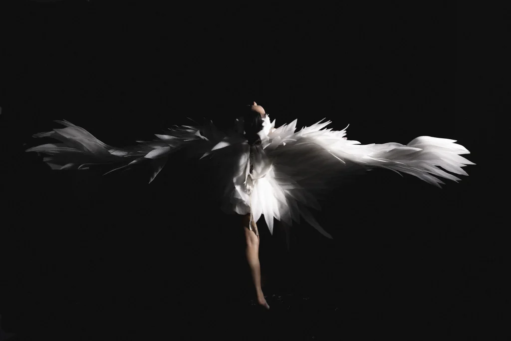 Dancer in white photographed against a black background