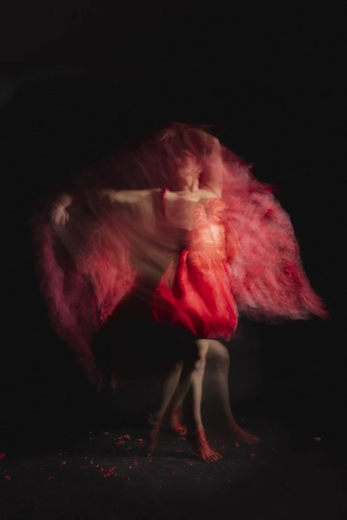 Dancer moving through red light and fabric