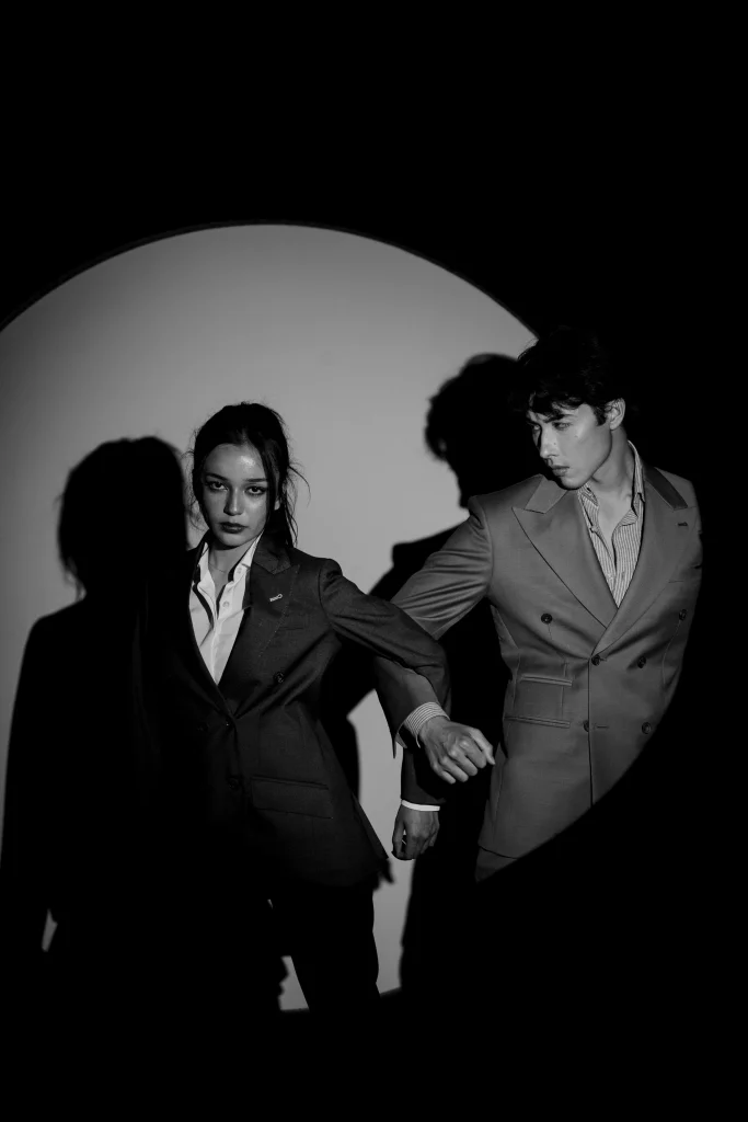 Two performers photographed in a monochrome studio composition