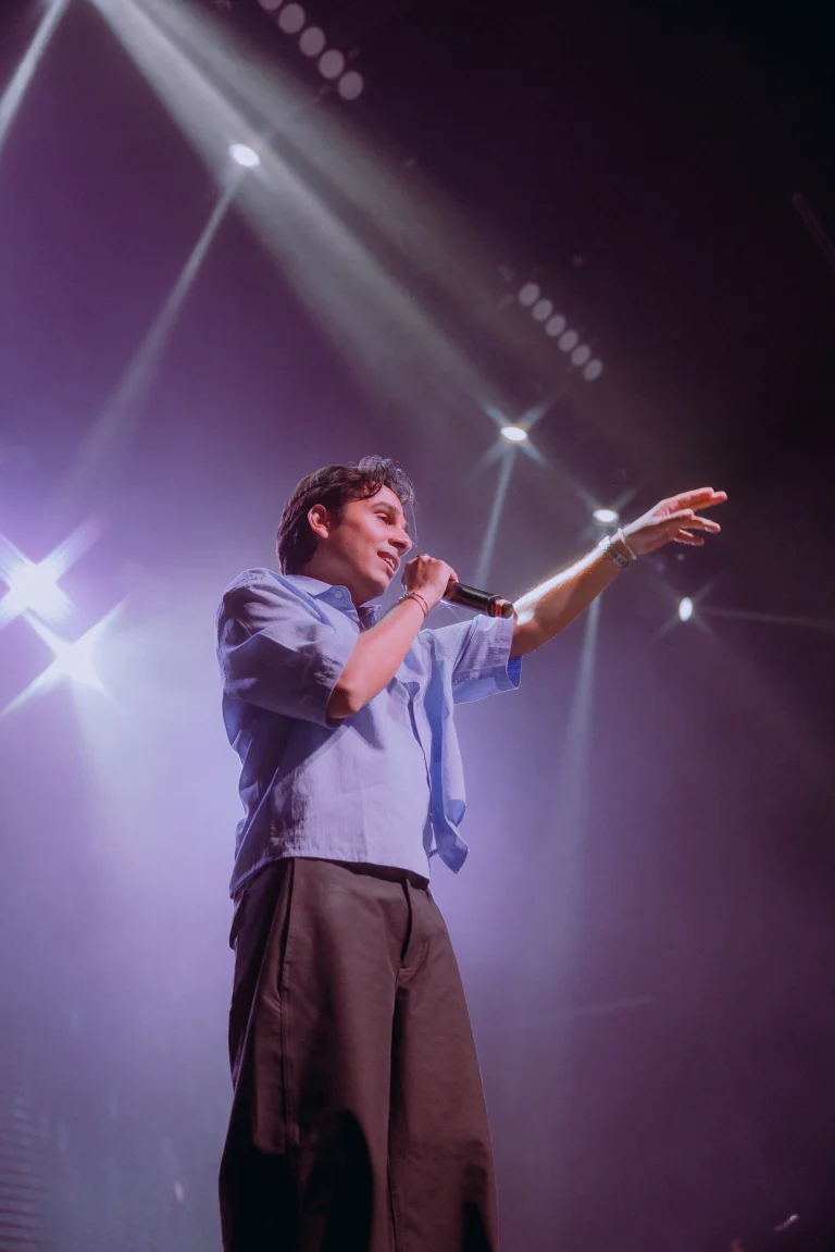 Singer performing beneath directional stage lights